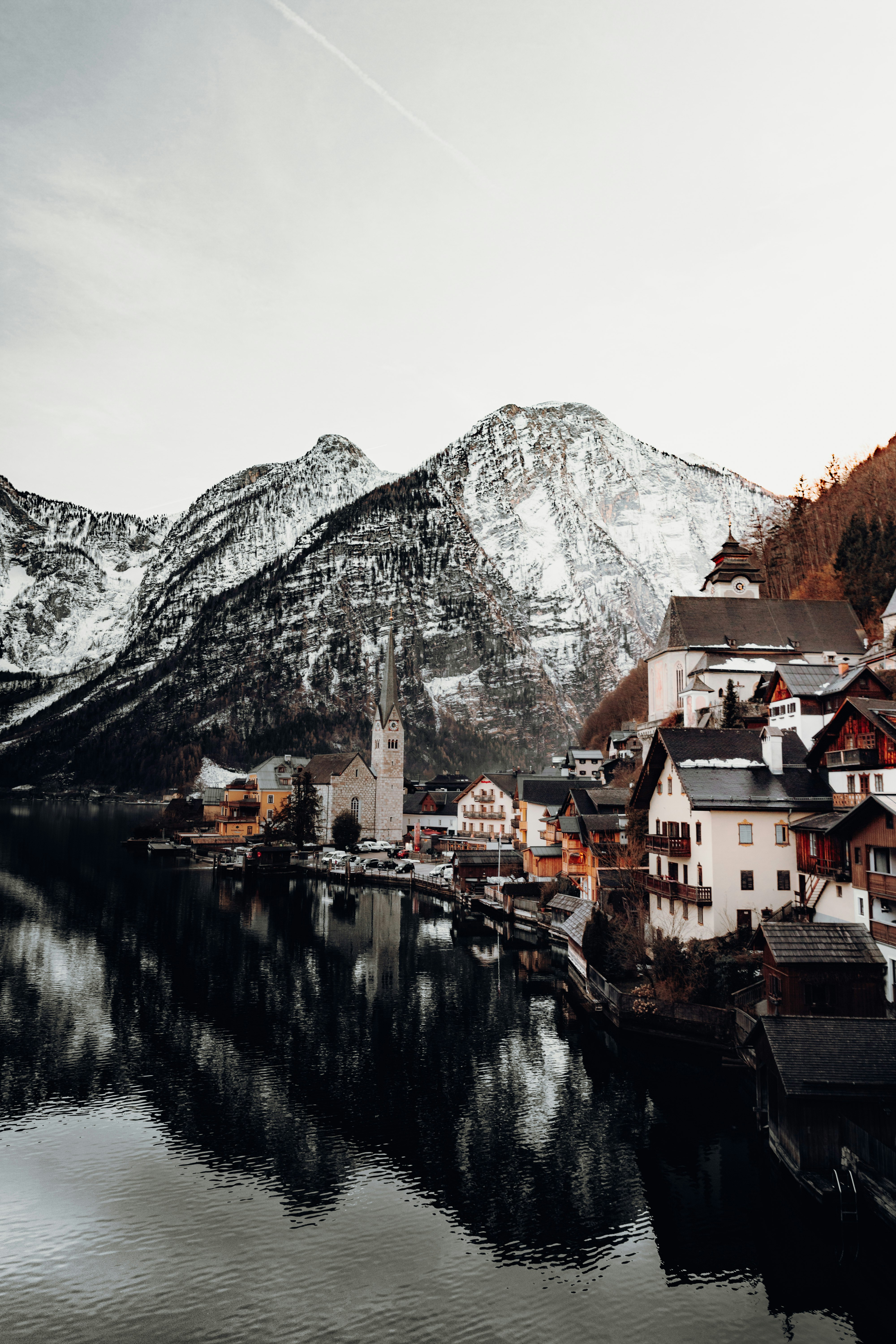 brown and white concrete houses near body of water and mountain